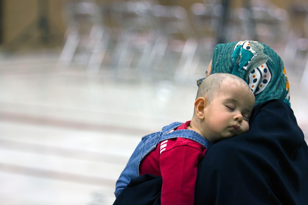 A baby sleeping peacefully against a caregiver's shoulder